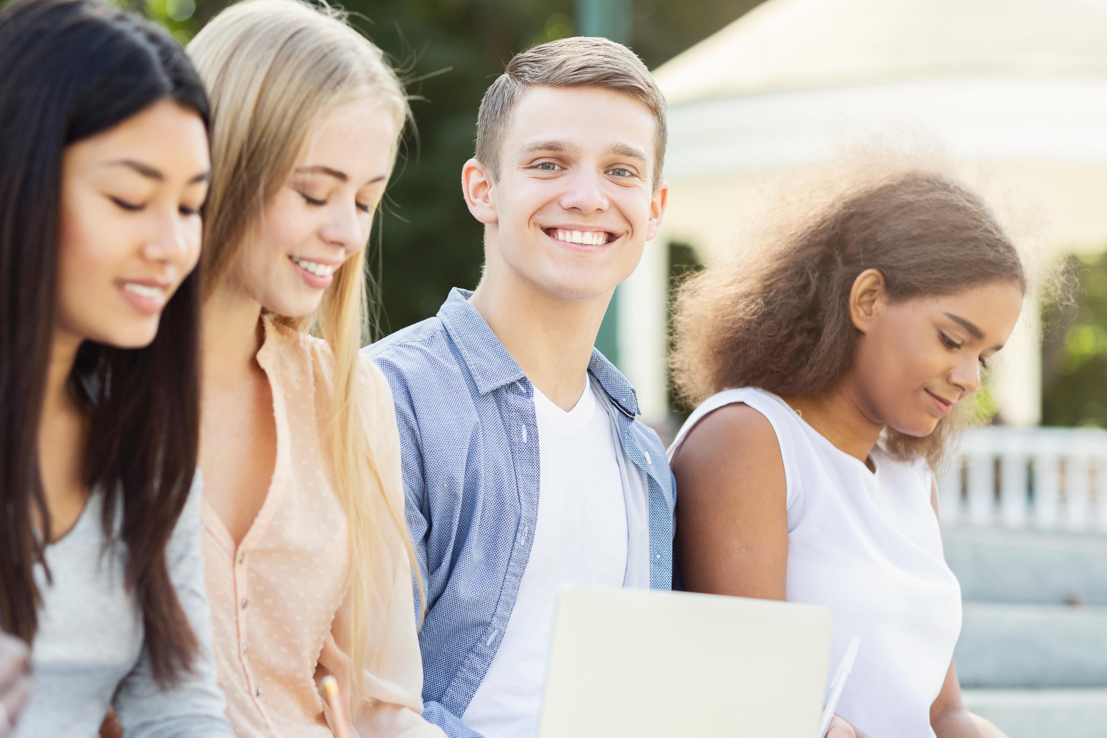 Students engaged in Digital SAT preparation, discussing problems with a tablet and study materials at a desk.