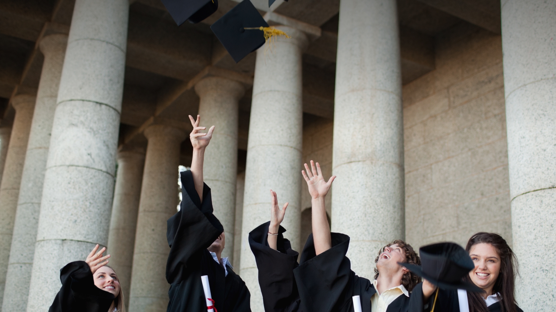 Graduating students celebrating their achievement by throwing caps in the air, symbolizing opportunities and bright futures ahead.